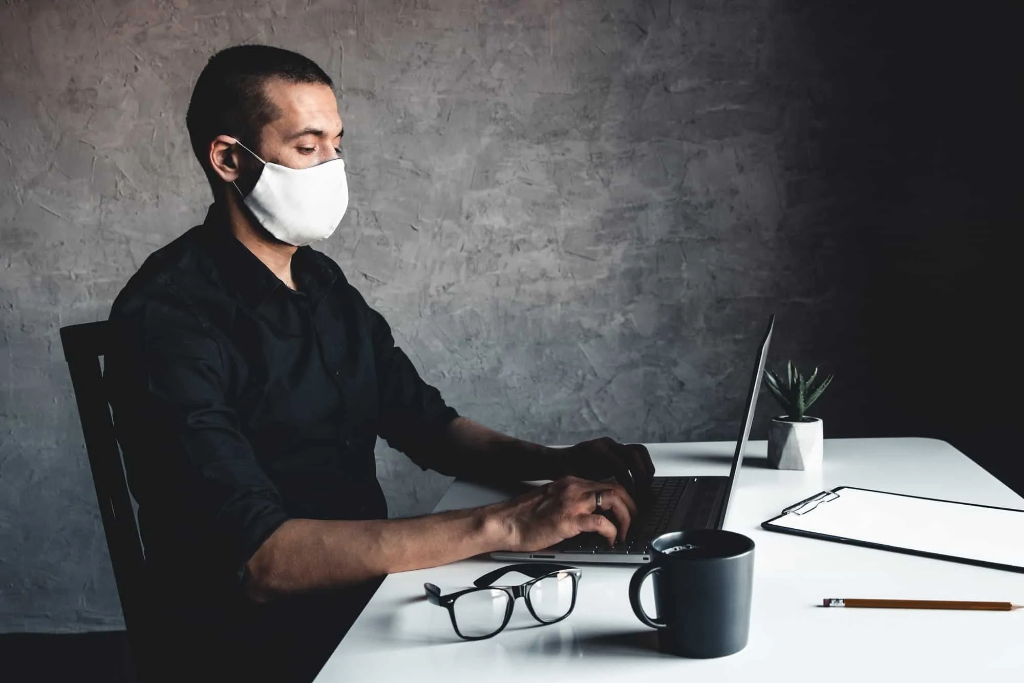 A masked man works at a computer. Pandemic, coronavirus, epidemic