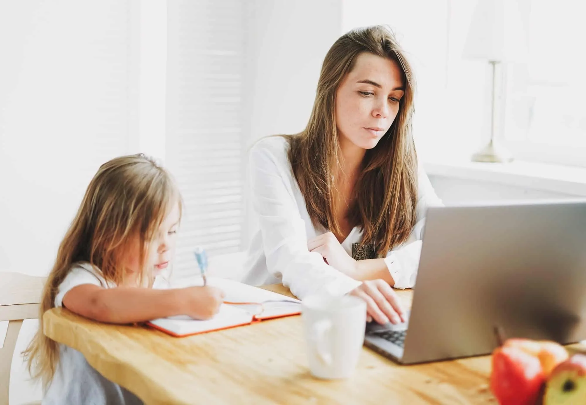 Working mom freelancer on laptop with little daughter